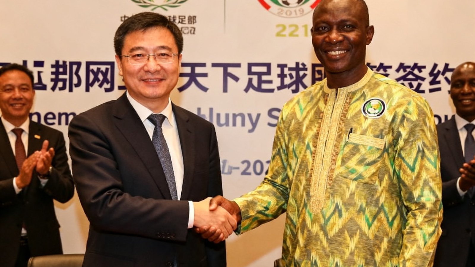 签约仪式现场，天下足球网代表与非洲足联官员握手合影，背景展示合作标识